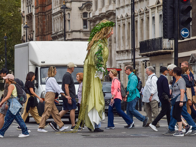 Un ambientalista vestito con un gigantesco costume da Madre Terra attraversa Parliament Square per sensibilizzare l'opinione pubblica sull'inquinamento dei fiumi nel Regno Unito