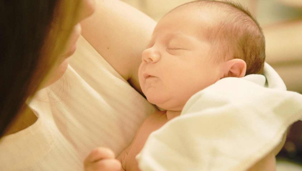 Neonato dorme sereno in braccio alla mamma