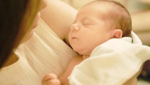 Neonato dorme sereno in braccio alla mamma