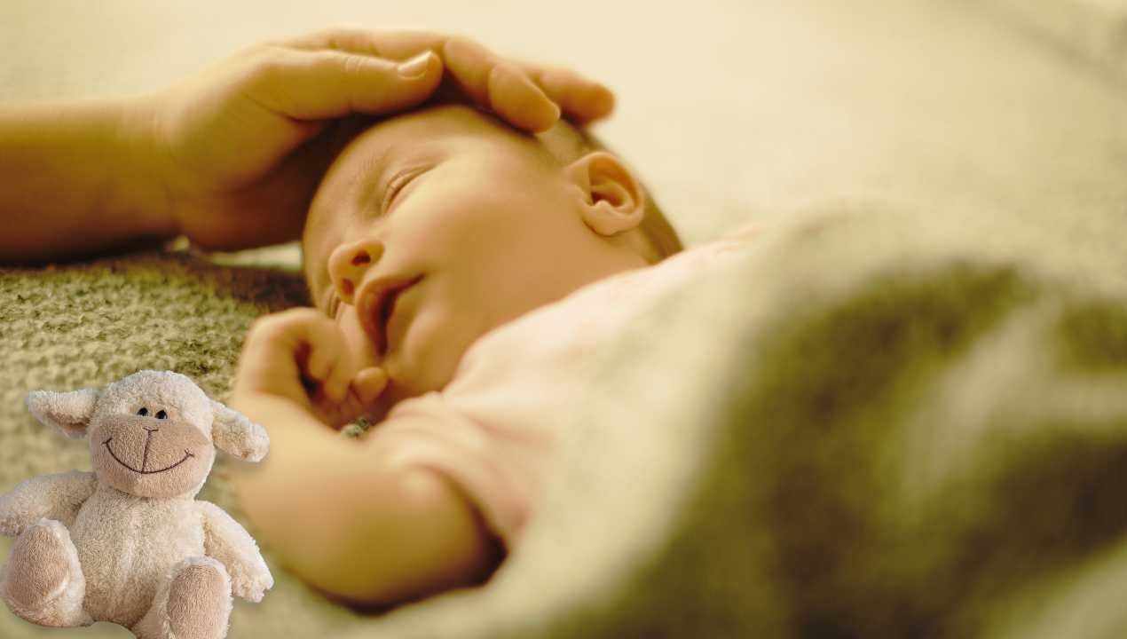 Neonato dorme mentre la mamma lo accarezza (canva) Lasvolta.it